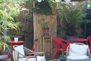 a patio with red chairs and a fence with plants at Inn 4 Bears in Nîmes