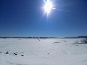 a sun is shining over a snow covered beach at Auberge de la rive de Charlevoix - Auberge familiale pour voyageurs de tous âges in Saint-Joseph-de-la-Rive