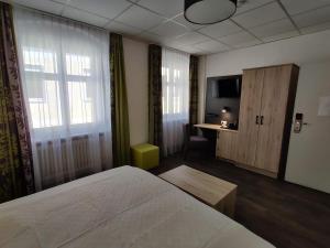 a bedroom with a bed and a tv and a desk at Hotel Goldene Traube in Günzburg