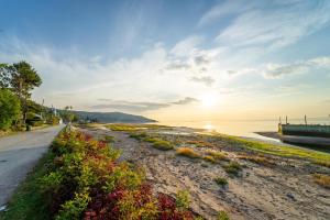 a road next to a beach with the sun setting at Auberge de la rive de Charlevoix - Auberge familiale pour voyageurs de tous âges in Saint-Joseph-de-la-Rive
