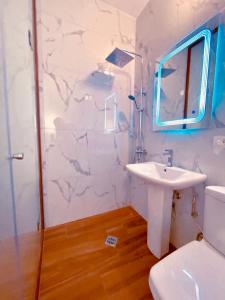 uma casa de banho branca com um lavatório e um espelho em ODA Guest House em Korçë