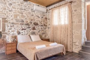 a bedroom with a bed and a stone wall at The Stone House of Iakovos in Kaloudhianá
