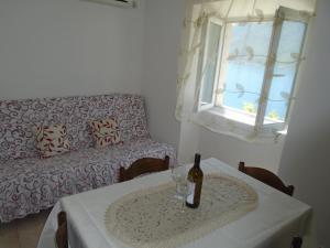 a room with a table with a bottle of wine and a couch at Apartments Jovanović in Perast