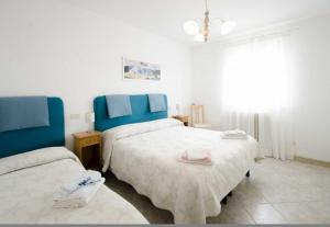 een slaapkamer met 2 bedden met blauwe hoofdeinden bij Maison La Vela in Forte dei Marmi