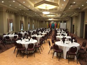 a banquet hall with white tables and chairs at Divya Sutra Plaza and Conference Centre Calgary Airport in Calgary