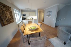 cocina y comedor con mesa de madera y sillas en Residenz Strandläufer en Wenningstedt