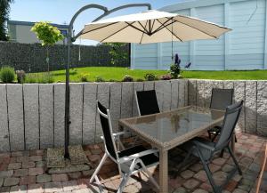 einen Tisch und Stühle mit Sonnenschirm auf einer Terrasse in der Unterkunft Casa Elea, die Ferienwohnung mit Terrasse und Garten am Tor zum Bodensee in Stockach