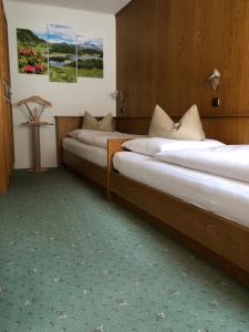2 camas en una habitación de hotel con pinturas en la pared en Haus Arnold Schranz, en Sankt Anton am Arlberg