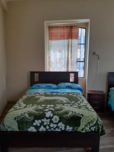 1 cama en un dormitorio con ventana y colcha en Hostal Mediodia, en Quito