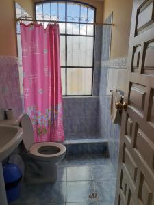 baño con cortina de ducha rosa y aseo en Hostal Mediodia, en Quito