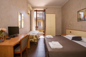 Zimmer mit 3 Betten und einem Schreibtisch mit einem Computer in der Unterkunft Hotel Angelica " Stazione Santa Maria Novella " in Florenz