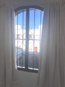 una ventana con cortinas blancas y vistas a un edificio en Cálido apartamento en Salta