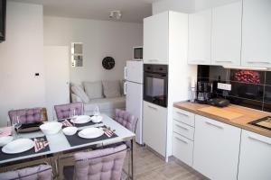 a kitchen with a table and purple chairs in a room at Apartment Gordon in Mali Lošinj