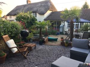 un jardin avec des chaises et une maison avec un barbecue dans l'établissement Guest Suite at 31 Little England, à Milborne Saint Andrew