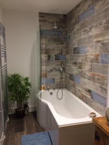 uma banheira na casa de banho com uma parede de azulejos em Guest Suite at 31 Little England em Milborne Saint Andrew