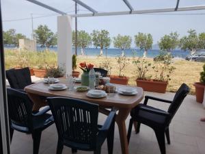 a wooden table and chairs with a view of the beach at MAREMARI VILLA in Ayía Marína