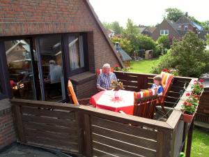 a man and a child sitting at a table on a deck at Haus Seerobbe-Obergeschosswohnung in Fehmarn