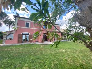 una grande casa rosa con un cortile verde di Antico Casale Edifizio a Viterbo