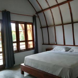 ein Schlafzimmer mit einem großen Bett und zwei Fenstern in der Unterkunft Gino's Place - Bungalows and Restaurant in Bukit Lawang