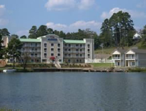 a large building next to a large body of water at Baymont on the lake by Wyndham Hot Springs in Hot Springs
