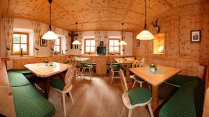 een restaurant met houten muren en tafels en groene stoelen bij Hotel Pension Geiger in Serfaus