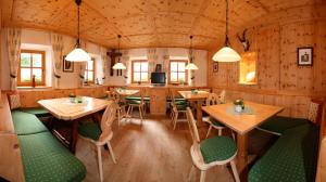 a restaurant with wooden walls and tables and green seats at Hotel Pension Geiger in Serfaus