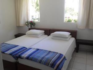 two beds in a small room with two windows at La Punta Apartamentos in Cabarete