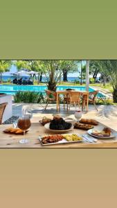 a table with plates of food and drinks and a pool at JCS SEIJAS APARTAMENT Recidence and Beach Club, 3E in Pajarito