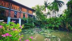 a house with a pond with lily pads in front of it at Twelve Cutting Units in Sukhothai