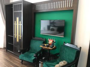 um quarto verde com duas cadeiras e uma mesa e uma televisão em Hanoi Center Silk Lullaby Hotel and Travel em Hanói