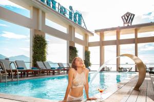 
a woman in a bikini standing in front of a swimming pool at Diamond Sea Hotel in Danang
