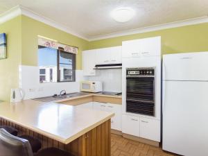 a kitchen with white cabinets and a white refrigerator at Champagne Court 1 in Tuncurry