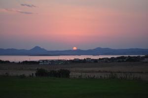 a sunset over the water with the sun in the distance at Villa Panorama in Moúdhros