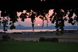 a sunset over a field with the sun in the sky at Villa Panorama in Moúdhros
