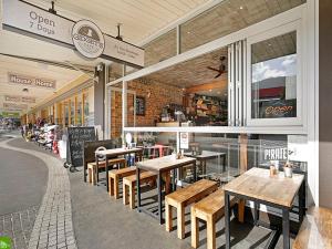 ein Restaurant mit Holztischen und -stühlen in einem Gebäude in der Unterkunft Sandon Point Coastal Abode in Bulli