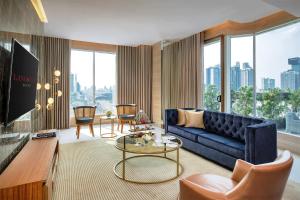 a living room with a blue couch and a large window at Lancaster Bangkok in Bangkok