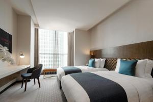 pokój hotelowy z dwoma łóżkami i krzesłem w obiekcie Lancaster Bangkok w mieście Bangkok