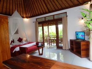 a bedroom with a bed and a television in a room at Amaya Cottage Ubud by Svaha Hospitality in Ubud