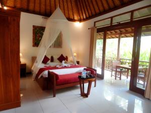 een slaapkamer met een rood bed met een baldakijn bij Amaya Cottage Ubud by SHM in Ubud