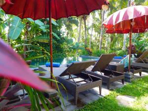 un patio con sillas y sombrillas junto a una piscina en Amaya Cottage Ubud by Svaha Hospitality, en Ubud