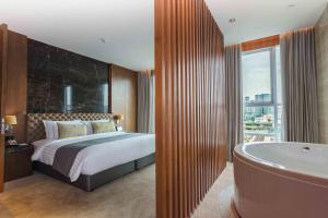 
a hotel room with a bath tub and a bed at Lancaster Bangkok - SHA Extra Plus in Bangkok
