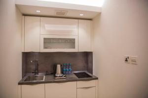 una cocina con armarios blancos y fregadero en Al Aryam Serviced Aparthotel, en Buraidah