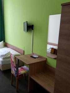 een kamer met een bed en een bureau met een spiegel bij Hotel Flora in Hannover