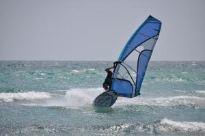 a person on a surfboard with a sail on the ocean at Villa Panorama in Moúdhros