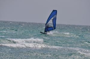 a person on a windsurfing board in the ocean at Villa Panorama in Moúdhros