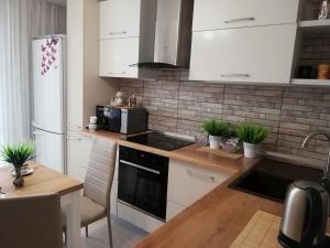 a kitchen with white appliances and a wooden table at Helena Apartments on Mira 61 in Mogilev