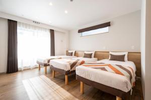 東京的住宿－Eisei Stay，一间卧室设有三张床和窗户。