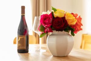 un jarrón blanco con un ramo de rosas y una botella de vino en Landhaus am Gries, en Lana