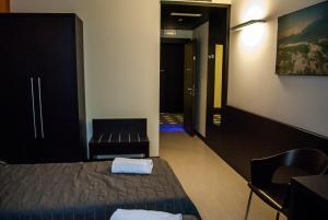 a room with a bed and a chair and a corridor at Vercelli Palace Hotel in Vercelli