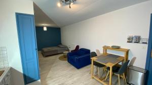 sala de estar con mesa y silla azul en Studio aux Sources de la Chabanne, en Saint-Hilaire-les-Courbes